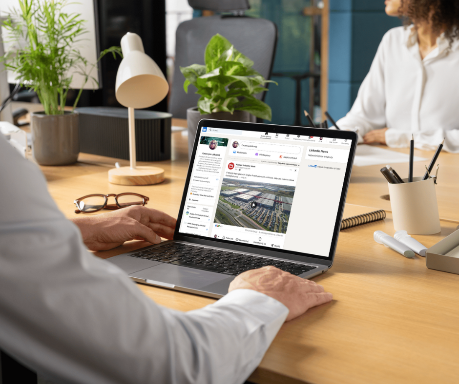 Dłonie mężczyzny przed komputerem na którym widoczny jest główny feed LinkedIn