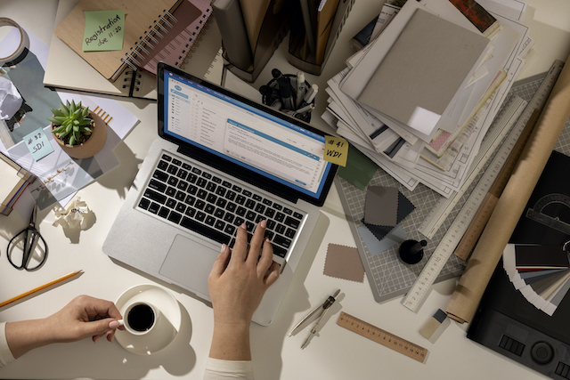 Widok na zagracone biurko z laptopem po środku